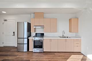 A kitchen with a refrigerator, oven, and sink.