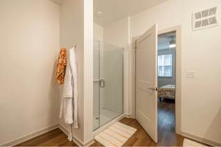 A white towel is hanging on a white wall next to a glass door.