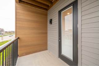 A balcony with a glass door and a black railing.