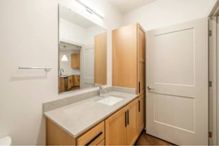 A bathroom with a sink, mirror, and wooden cabinets.