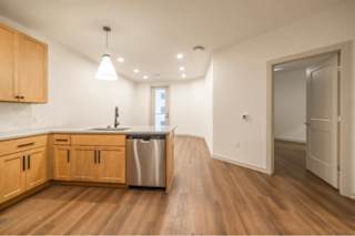A kitchen with wooden cabinets and a stainless steel dishwasher.