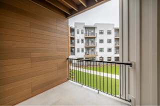 A balcony with a black railing and a wooden wall.