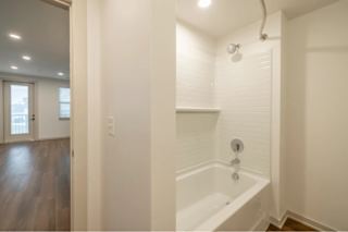 A white bathroom with a tub and a door.