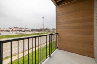 A balcony with a black railing and a wooden wall.