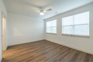 A room with wooden floors and two windows.