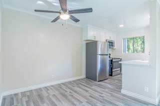 a living room with a ceiling fan and a kitchen in the background