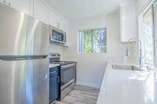 a small kitchen with white cabinets and stainless steel appliances