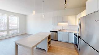 an empty kitchen with a table and a refrigerator