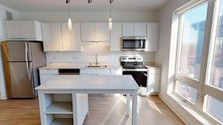 a kitchen with white cabinets and a large window