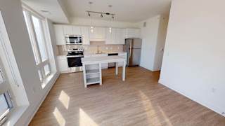 an empty kitchen with a white island and a refrigerator