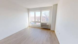 an empty living room with a window and wood floors