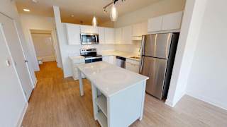 a kitchen with a white island and a stainless steel refrigerator