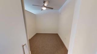 an empty room with a ceiling fan and a carpet