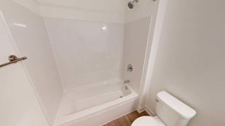 a white bathroom with a white toilet and a bath tub