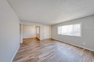 A room with wooden flooring and a window with blinds.