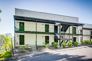 A white building with green doors and a staircase.