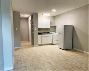A kitchen with white cabinets and a refrigerator.