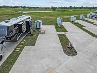 A row of portable toilets are lined up on a concrete path.