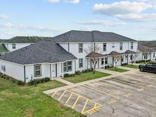 A white building with a parking lot in front of it.