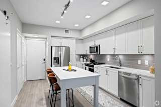 A modern kitchen with a white island and stainless steel appliances.