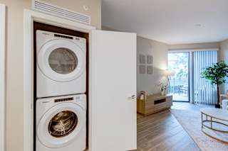 A white washing machine is in a cabinet in a room with a wooden floor.