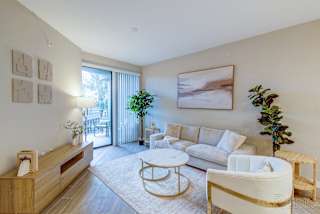 A living room with a white couch, a coffee table, and a large painting on the wall.