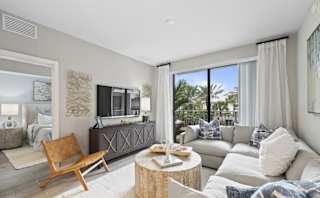 A living room with a wooden chair and a grey couch.