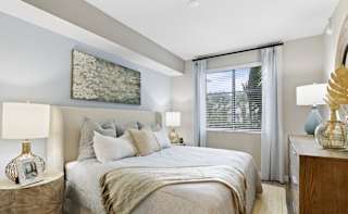 A bedroom with a large bed and a painting on the wall.