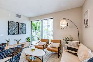 A living room with a white couch, a coffee table, and a large window.