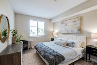 A bedroom with a large bed, a mirror, and a painting on the wall.