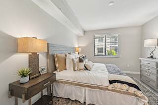 A well-lit bedroom with a large bed and a nightstand with a lamp.