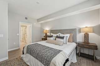 A bedroom with a large bed and a nightstand with a lamp.