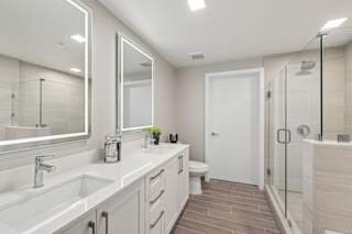 A bathroom with a white sink, mirror, and toilet.