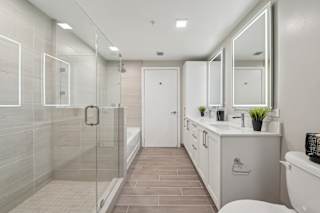 A modern bathroom with a walk-in shower and double sinks.