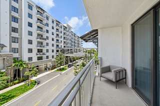 A balcony with a chair overlooks a street with apartment buildings.