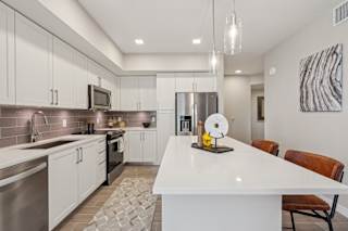 A modern kitchen with a white island and stainless steel appliances.