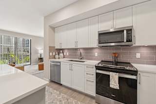 A modern kitchen with a stainless steel oven and white cabinets.