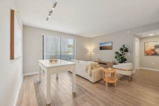 A living room with a white couch, a wooden coffee table, and a plant.