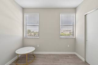 A room with a round table and two windows with blinds.