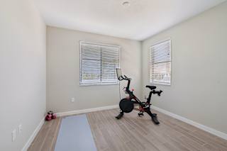 A room with a stationary bike and a yoga mat.