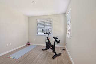 A room with a stationary bike and a yoga mat.