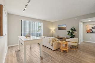 A living room with a white couch, a wooden coffee table, and a painting on the wall.