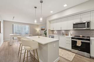A modern kitchen with a white island and bar stools.