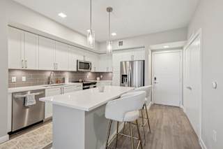 A modern kitchen with a white island and stainless steel appliances.