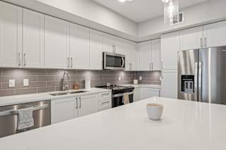 A modern kitchen with a white countertop and stainless steel appliances.