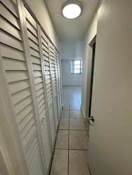 A long hallway with white walls and a light on the ceiling.