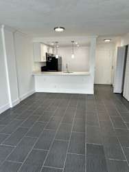 A kitchen with white cabinets and a black fridge.