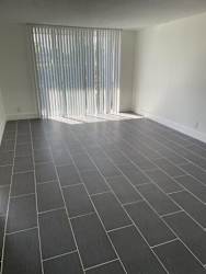 A room with a black tile floor and a window with blinds.