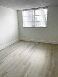 A room with a window and wooden flooring.