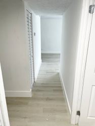 A long white hallway with a door on the right.